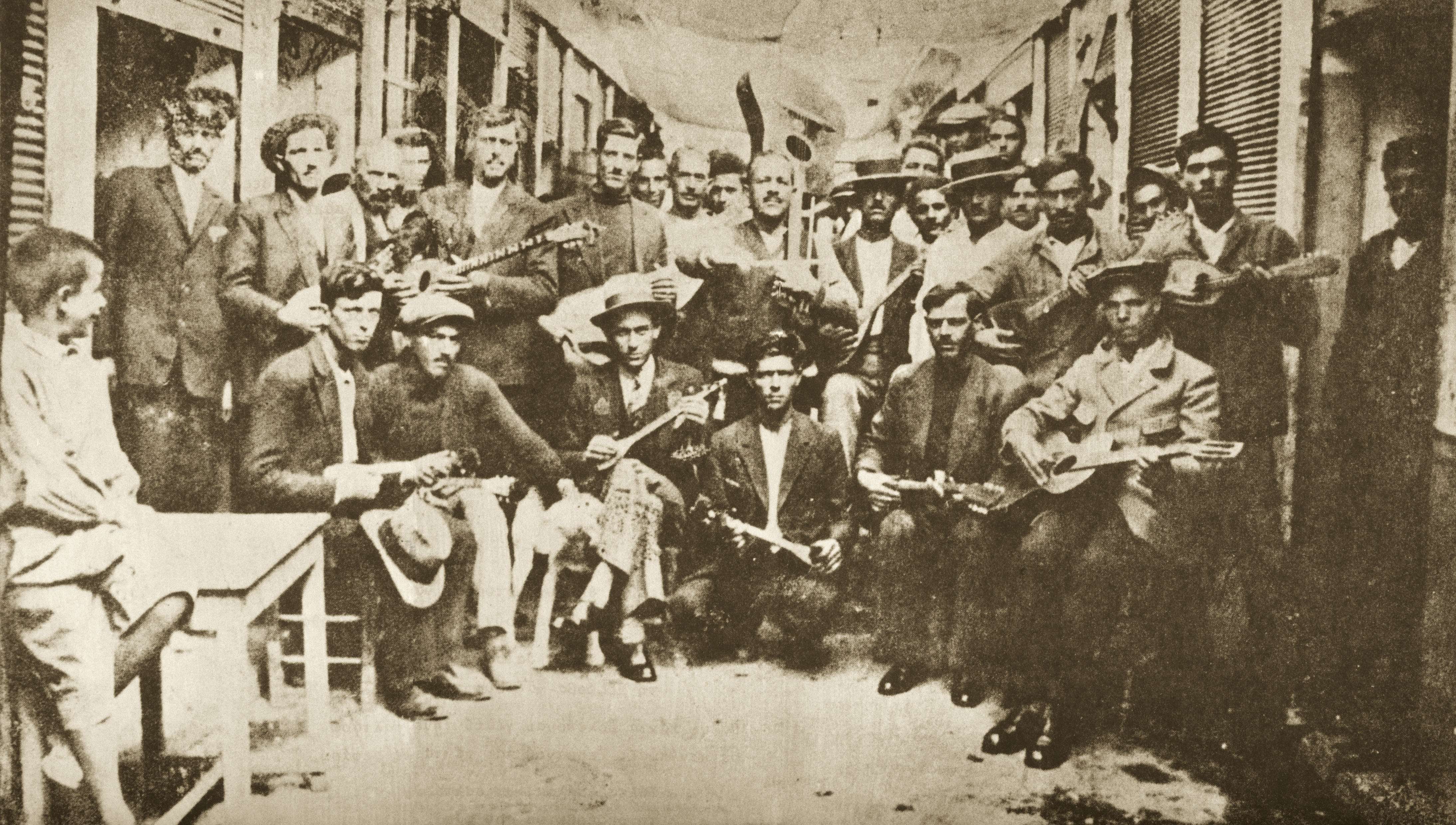 Ρεμπέτες στο Καραϊσκάκη, Πειραιάς (1933). Αριστερά ο Μάρκος Βαμβακάρης με μπουζούκι, στο κέντρο ο Μπάτης με την κιθάρα..
